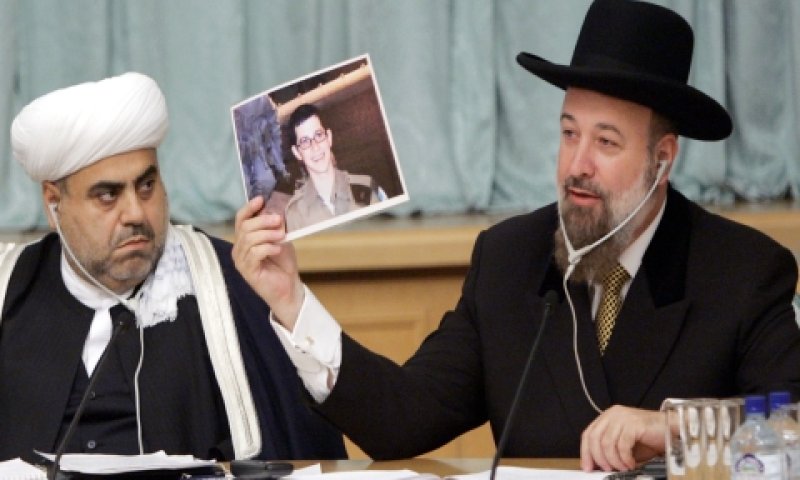 הרב הראשי, הרב יונה מצגר מנופף בתמונתו של גלעד שליט מול הנציג האירני. צילום: NFC