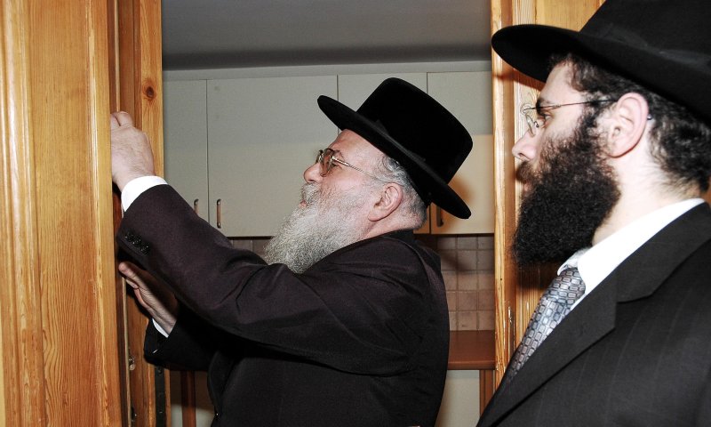 הרב ירמיה כהן ראב"ד פאריז קובע את המזוזה במשרדי המרכז בבריסל. לצידו,  המזכ"ל מנחם מרגולין