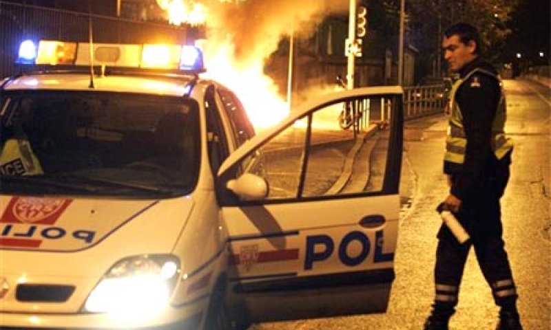 שוטר צרפתי מול מכונית שעולה באש, בדרום פריז. צילום: אי. פי.