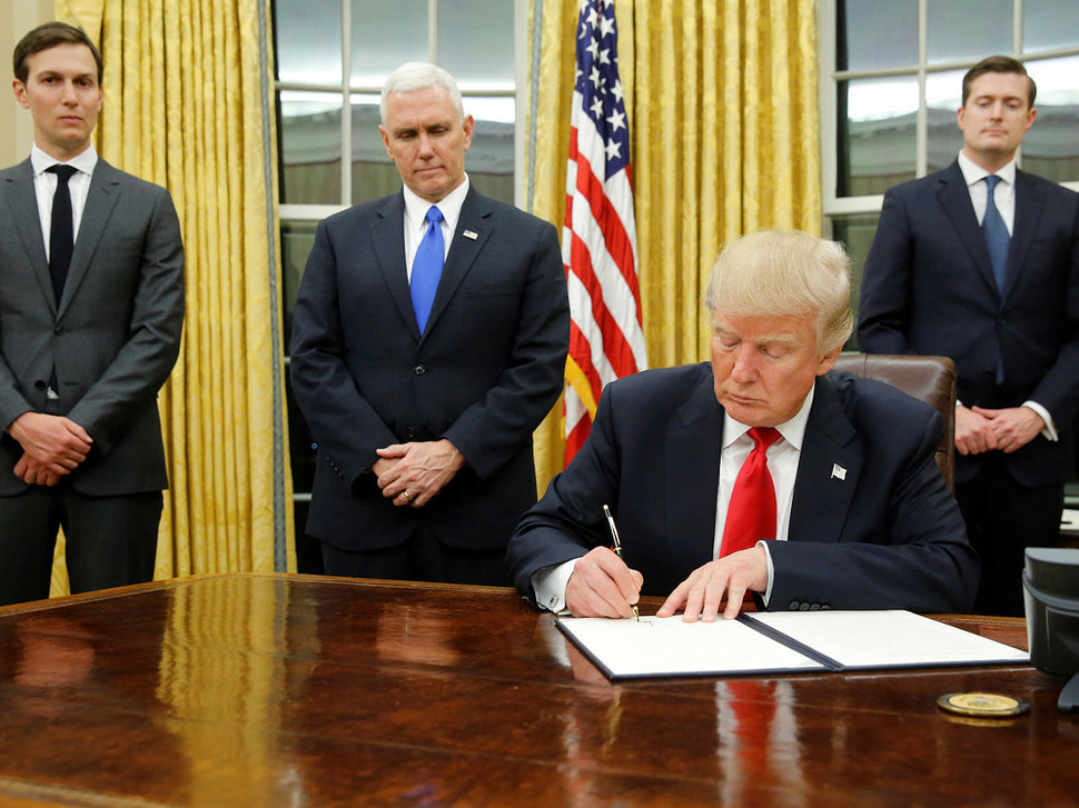 טראמפ חותם על הצו, לראשונה בבית הלבן. משמאל: חתנו קושנר
